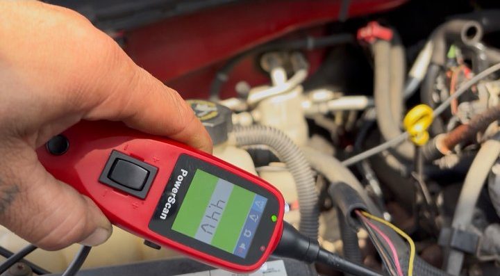 A circuit tester reading a live engine bay